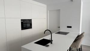 a white kitchen with a desk with a lamp on it at The 996 Business Flat in Lommel