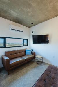 a living room with a leather couch and a flat screen tv at Ola in San Carlos