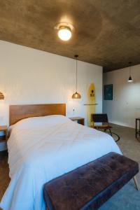 a bedroom with a large white bed and a surfboard at Ola in San Carlos
