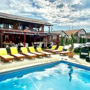 a pool with yellow lounge chairs next to a house at Casa David Turda in Turda