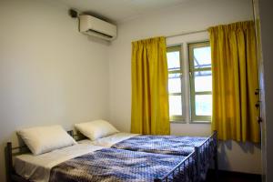 a bedroom with a bed and a window with yellow curtains at Nr 1 Spot in Paramaribo