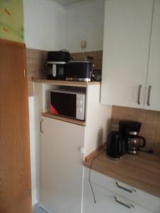 a kitchen with a microwave on top of a refrigerator at Heikeland in Südbrookmerland +6 photos