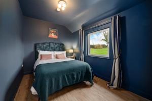 a blue bedroom with a bed and a window at The Meadows at Marlhill in Tipperary