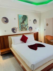 a bedroom with a large white bed with red pillows at MAG Palace Hotel in Bissau