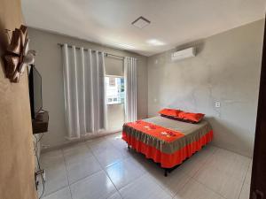 a bedroom with a bed with red sheets and a window at Apartamento tecnoshow in Rio Verde