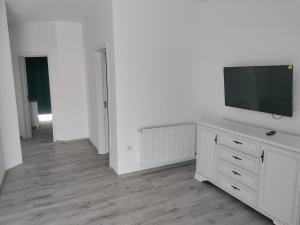 a white room with a tv on top of a dresser at Park & Rest Apartment in Mărtineşti