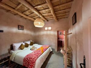 a bedroom with a bed and a chandelier at Maroc des Merveilles - Chez L'habitant in El Kelaa des Mgouna