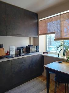 a kitchen with black cabinets and a table and a window at BOHO Ogre in Ogre