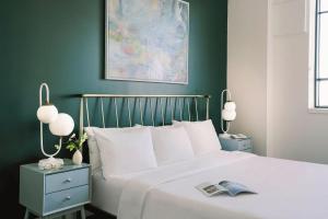 a bedroom with a white bed with green walls at The Cove Hotel - Plateau Mont-Royal in Montreal