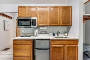 a kitchen with wooden cabinets and a sink and a microwave at Pet Friendly Riverside Studio in Downtown Bend in Bend