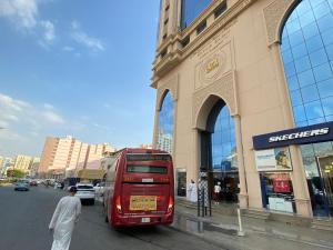 a red double decker bus parked in front of a building at فندق العزيزية توصيل للحرم in Mecca