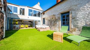 a yard with green lawn chairs and a house at Maison ALMA Piscine -Baby Foot - Cheminée- Jacuzzi in Vantoux