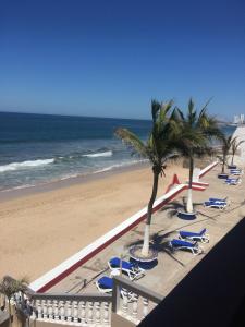 a beach with chairs and palm trees and the ocean at Hacienda Blue Bay in Mazatlán +11 photos