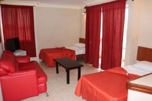 a hotel room with two beds and a red chair at Hacienda Blue Bay in Mazatlán