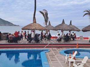 a group of people sitting around a pool next to the ocean at Hacienda Blue Bay in Mazatlán