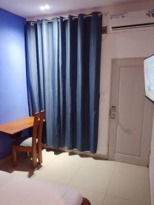 ein Zimmer mit einem Tisch und einem blauen Vorhang in der Unterkunft Hôtel Semto in Edéa