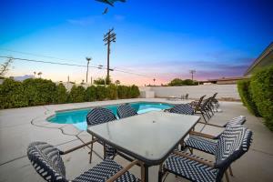 a table and chairs next to a swimming pool at Cozy Retreat with Pool, BBQ and Fire Pit in Indio