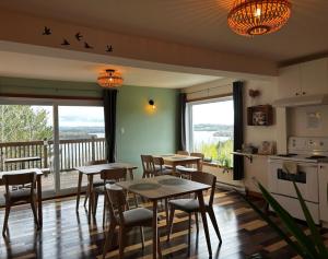 eine Küche und ein Esszimmer mit Tischen und einem Balkon in der Unterkunft Le Perchoir in Saint-Félix-d'Otis