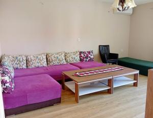 a living room with a purple couch and a coffee table at Harmony Apartment in Strumica