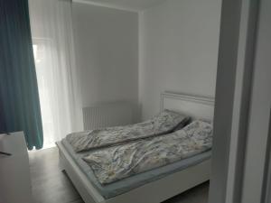 an unmade bed in a bedroom next to a window at Park & Rest Apartment in Mărtineşti