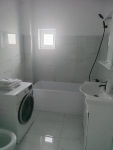 a white bathroom with a washing machine and a sink at Park & Rest Apartment in Mărtineşti
