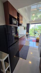 a kitchen with a black refrigerator and a living room at PB325 Ideal studio apartment in Phuket in Ban Mai Salae