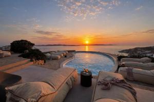 a pool with couches and a sunset in the background at Villa Tavani Agios Ioannis Mykonos in Agios Ioannis Mykonos