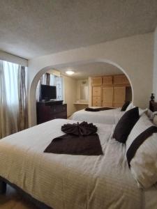 a bedroom with a large white bed with an arch at Hotel Vilamiño in Aguascalientes