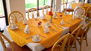 a dining room table with yellow table cloth and chairs at Hotel Vilamiño in Aguascalientes