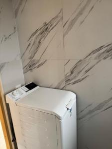 a white refrigerator in a kitchen with marble walls at Sosnowe Zacisze in Dębki
