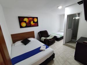 a bedroom with a bed and a chair in a room at Hotel Madeleine Norte in Barranquilla