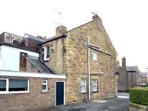 an old brick building with a blue door at Hallbank Hideout in Amble +4 photos