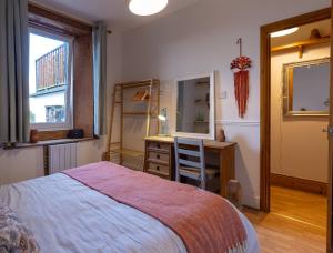 a bedroom with a bed and a desk and a mirror at Hallbank Hideout in Amble