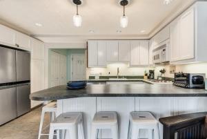 a kitchen with white cabinets and a counter with stools at Riverfront Cottage - Steam Room & Pet Friendly in Bend +34 photos