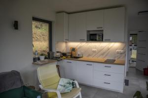 a kitchen with white cabinets and a yellow chair at Chatka Bratka in Kletno