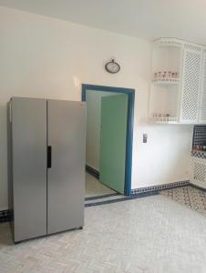 a room with a refrigerator and a clock on the wall at Bluegreen Guest House Marrakech in Aït Amara