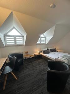 a bedroom with a bed and chairs in a attic at Hotel Bergschlößchen in Pockau