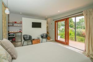 a bedroom with a bed and a sliding glass door at Studio 40 in Coromandel Town