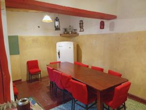 a dining room with a table and red chairs at Posada Las Piedras in Tilcara