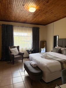 a bedroom with a large bed and a chair at Soulfenda guest house in Graskop