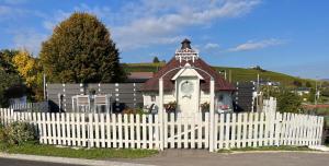 a white picket fence in front of a small church at B&B Chalet Grillkota in Trasadingen