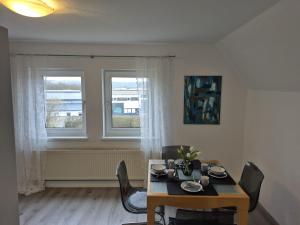 a dining room with a table and chairs and two windows at Solarhaus Guxhagen in Guxhagen