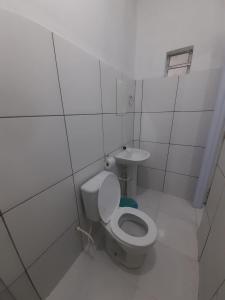 a white bathroom with a toilet and a sink at Pousada JM in Salgueiro