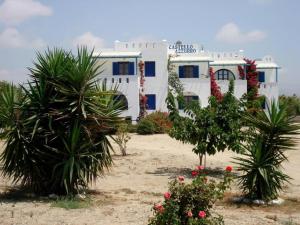 a white building with palm trees in front of it at Castello Azzurro in Agia Anna Naxos