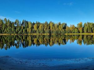 a lake with trees reflecting in the water at The River House & Riverside Sauna in Kokkola