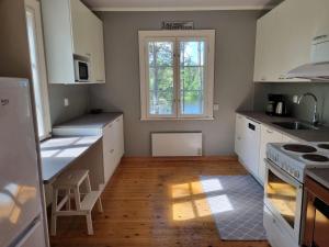 a kitchen with white cabinets and a wooden floor at The River House & Riverside Sauna in Kokkola