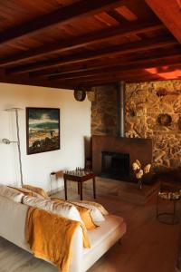 a living room with a stone fireplace and a couch at Casa do Cebro Casa con piscina y jacuzzi privados in Santiago de Compostela