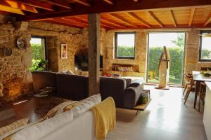 a living room with couches and a stone wall at Casa do Cebro Casa con piscina y jacuzzi privados in Santiago de Compostela