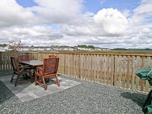 a table and chairs on a patio with a fence at Seaview in Garlieston