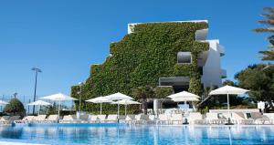 a swimming pool with chairs and umbrellas in front of a building at BLUESEA Ses Cases d'Or in Cala d´Or